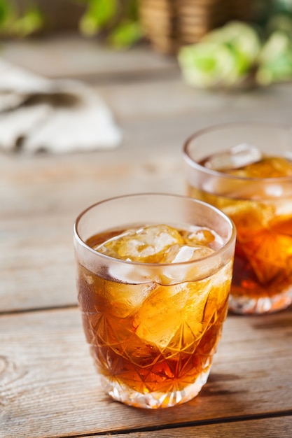 Old fashioned italian cocktail negroni with dry gin, campari, martini rosso vermouth and ice on a wooden table. Summer refreshing beverage