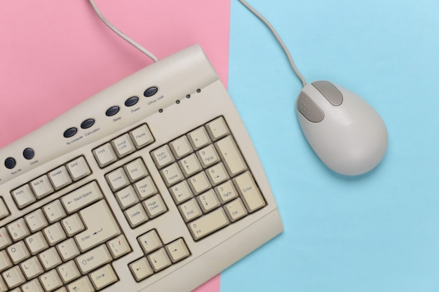 Old-fashioned retro keyboard and pc mouse on a blue-pink pastel. Retro computer