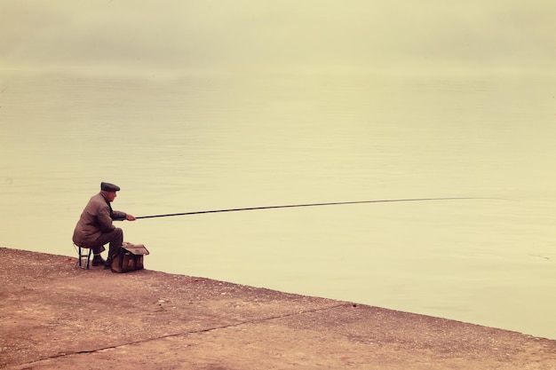 Old fisherman sitting on a wharf