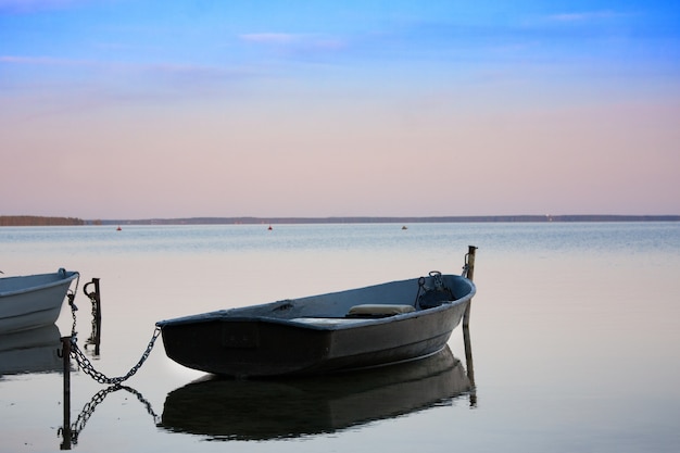 Old fishing boats with chain on lake at sunset