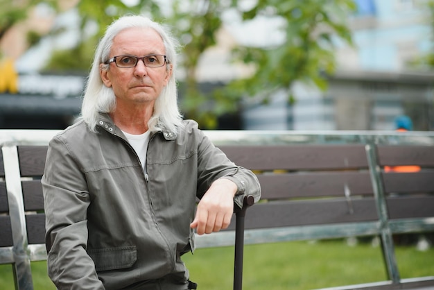 Old grayhaired man rest on the bench in summer park