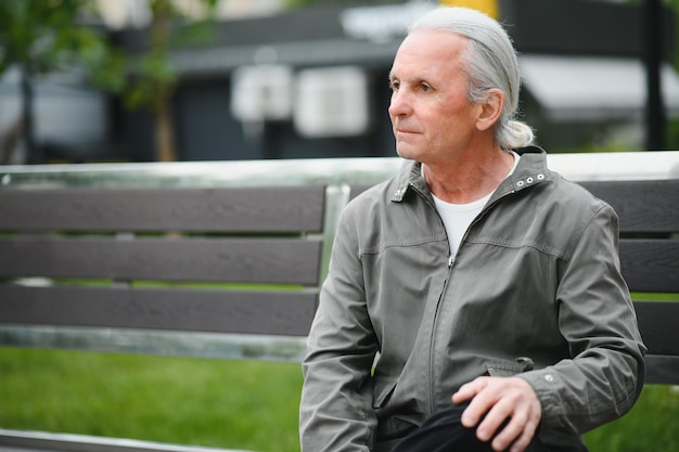 Old grayhaired man rest on the bench in summer park