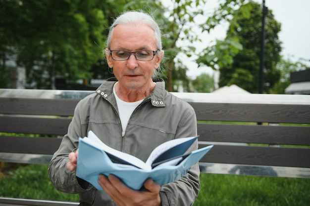 Old grayhaired man rest on the bench in summer park