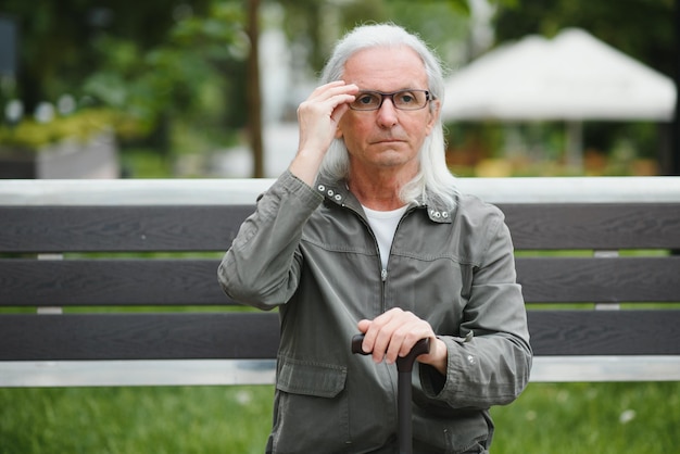 Old grayhaired man rest on the bench in summer park