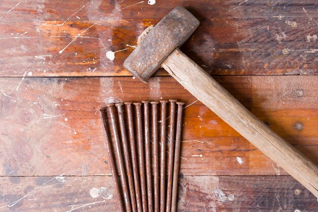 Old hammer with rusty nails and wooden background