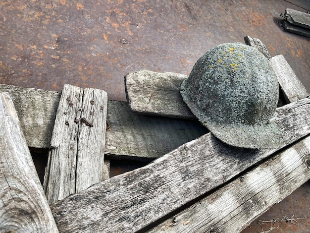 An old helmet overgrown with lichen lies on the boards