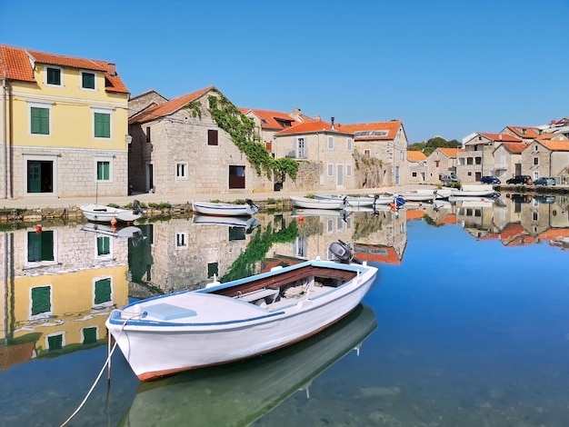 Old historic houses in Vrboska village, Hvar island, Dalmatia, Croatia, Europe. Fisherman boat with reflection. Travel and vacation destination. Old fisherman village, popular tourist destination