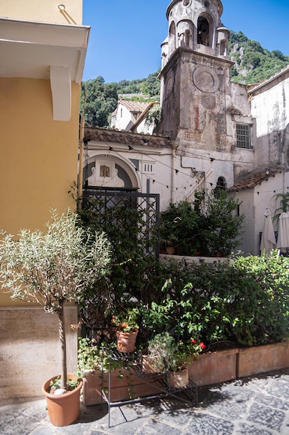 Old historic shabby romantic streets of southern Italy in the city of Amalfi Narrow vintage streets turns doors bathed in summer sun and surrounded by green trees