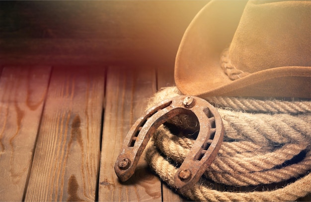 Photo old horseshoe , lariat lasso and cowboy hat on background