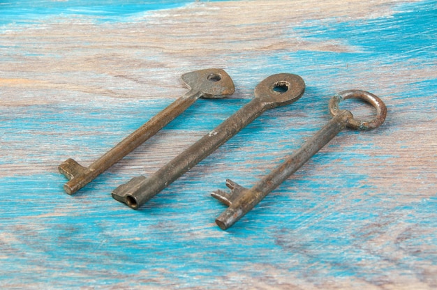 Old iron keys, detail of a classic metal keys on wooden background. Copy space for text`