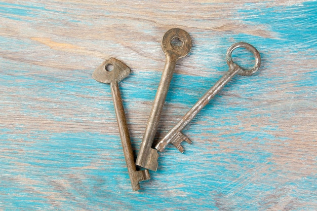 Old iron keys, detail of a classic metal keys on wooden background. Copy space for text`