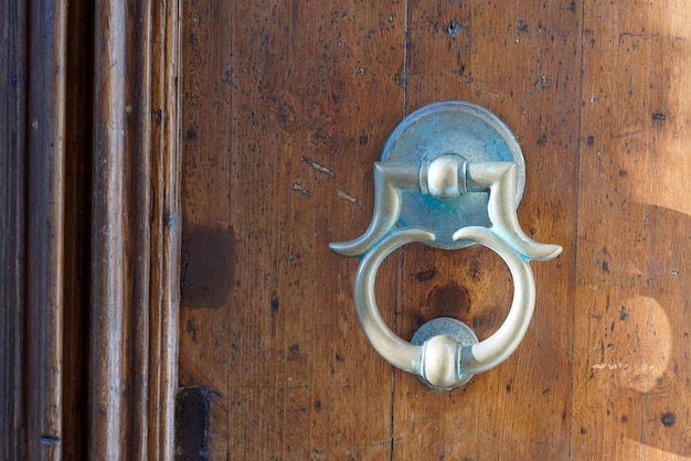 Old iron ring on wooden classic door for knocking on facade house