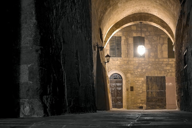 Old Italian town of Sorano at night. The stone arch and the old house are lit by a street lamp