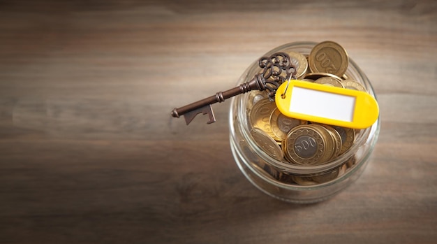 Old key and stack of coins on jar