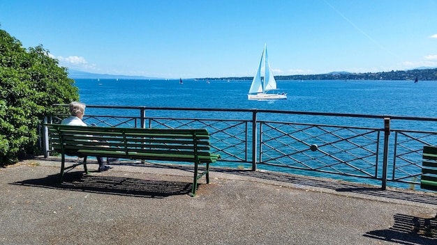 An old lady is watching the yacht in peaceful lake view in Geneva