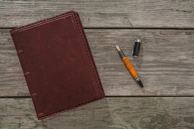 Old leather notebook and fountain pen on old wooden boards