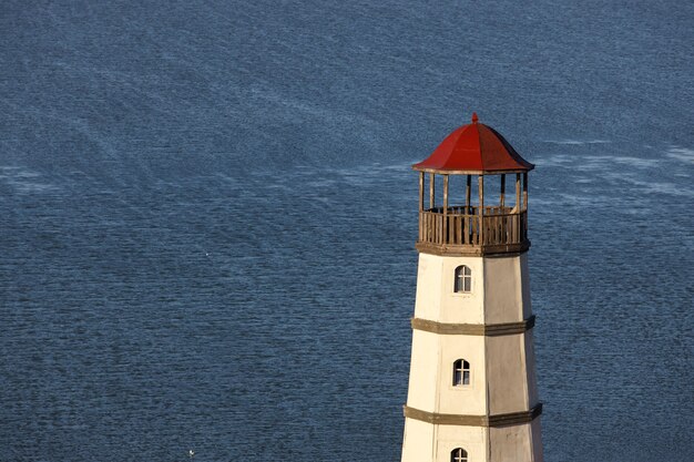 Old lighthouse with a red roof on the sea shore in the morning.