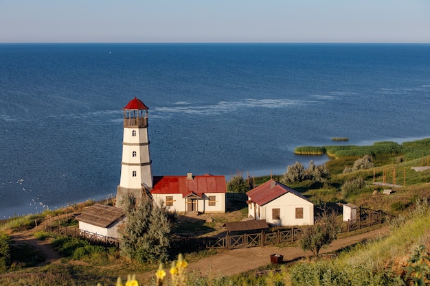 Old lighthouse with a red roof on the sea shore in the morning.