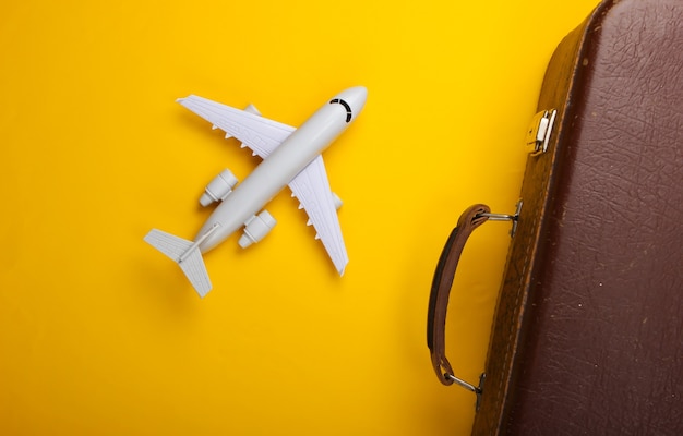 Old luggage and airplane figurine on yellow surface