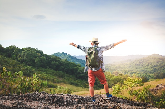 old man carrying a backpack, hiking and standing on a high mountain He is happy. Senior travel concept