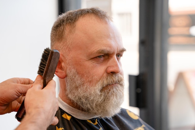 An old man enjoing haircut by a master in a barbershop An old man gets a stylish haircut