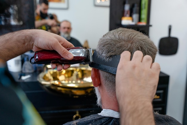 An old man enjoing haircut by a master in a barbershop An old man gets a stylish haircut