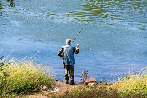 An old man is fishing, a fisherman, spending time in nature.