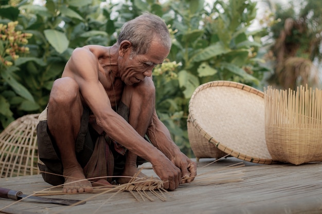 old man is weaving bamboo.