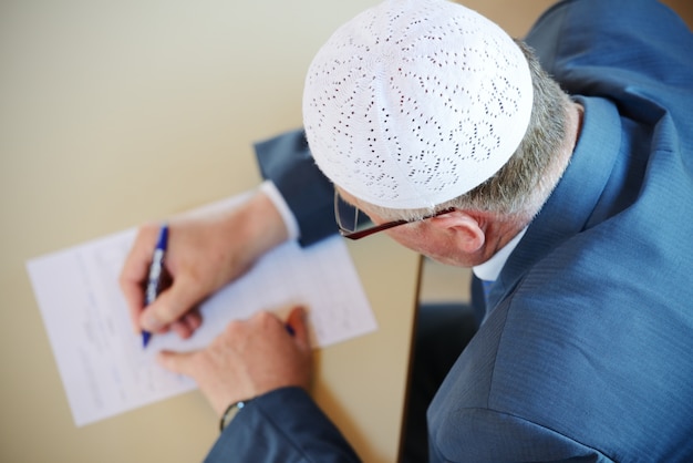 Old man writing with selective focus image