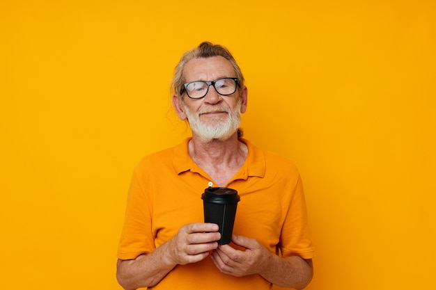 Old man in a yellow Tshirt a glass with a drink monochrome shot