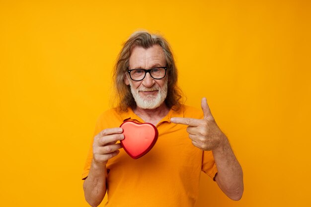 Old man yellow tshirt and glasses posing heartshaped box cropped view