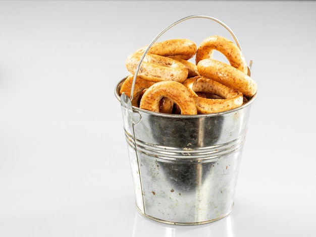 Old metal kitchen bucket with crispy bagels on a white background