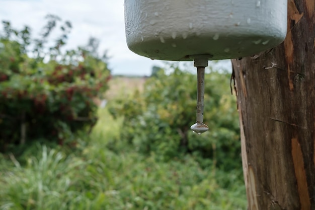 Old metal washbasin attached to a wooden post in a courtyard in the countryside