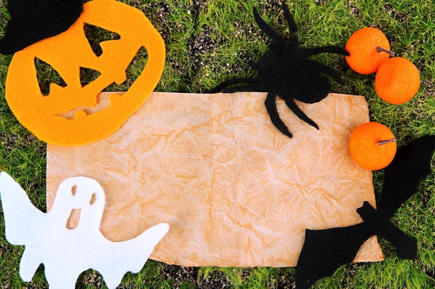 Old paper with Halloween decorations on green moss background