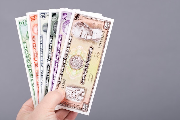 Old Peruvian money in the hand on a gray background