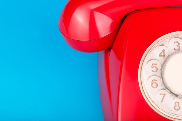 Old red telephone on a blue surface