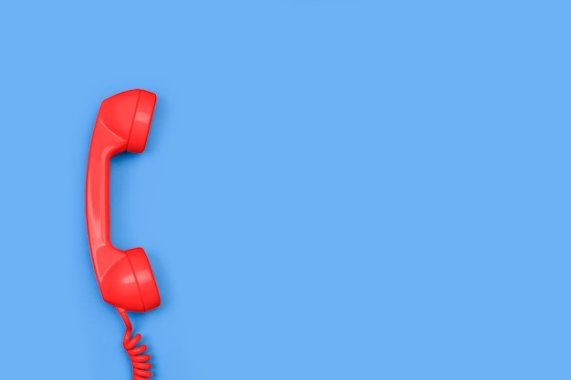 An old red telephone receiver on a blue background