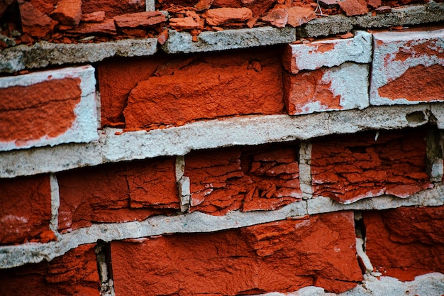 Old red and yellow bricks on the wall texture with pieces of plaster and paint