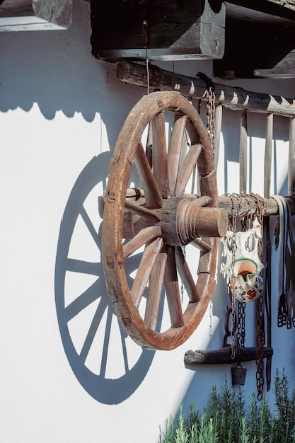 Old rural house and courtyard with a wooden staircase and cart wheel on a white wall in the ethnographic village of Holloko in Hungary close up