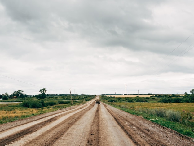 An old rural road The road is without asphalt Power poles and overcast sky