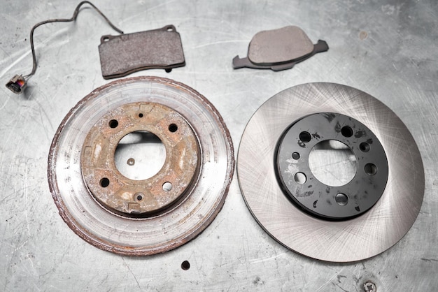 Photo old rusty brake disc and new disc front disk break pads change the old to new brake disc on car in a