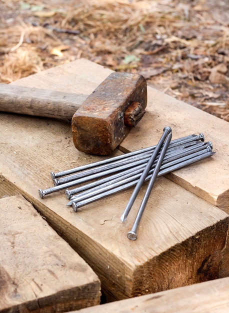 Old rusty hammer and nails lying on wooden bars