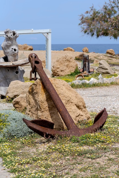 An old rusty iron anchor lies on the beach closeup