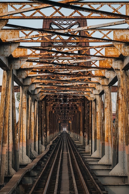 Old rusty iron traditional railway Long Bien bridge structure over the road in Hanoi city