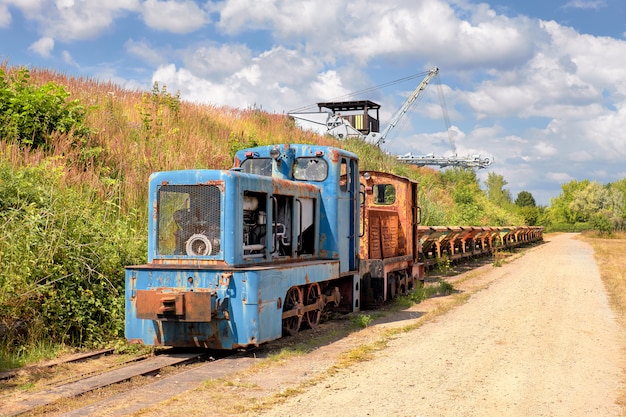 Old Rusty locomotive with a row of coal vagons and  bucket chain excavator