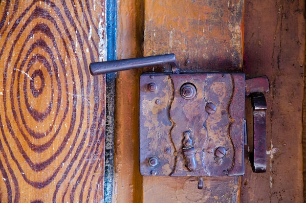 Old rusty metal door lock Dilapidated wooden door The entrance to the ancient Catholic temple Keyhole closeup