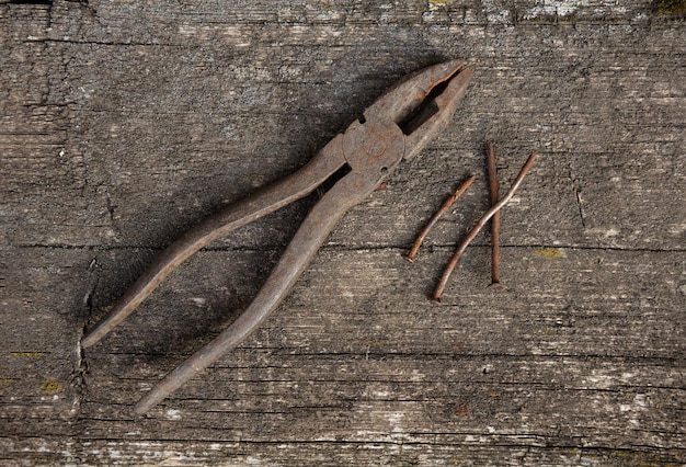 Old rusty pliers and nails on a wooden space