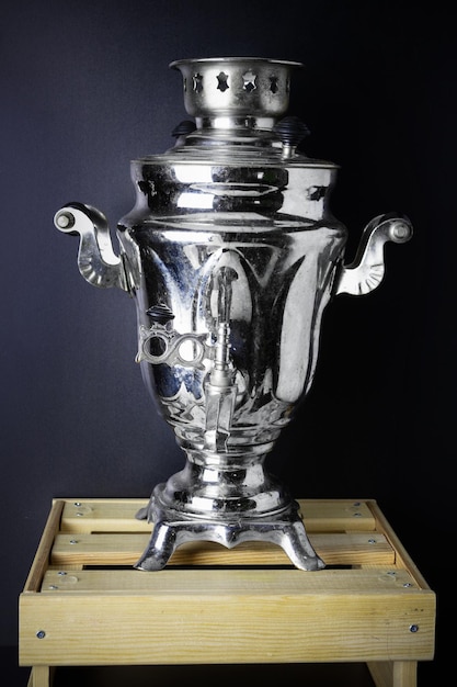 Old samovar on wooden box on black background