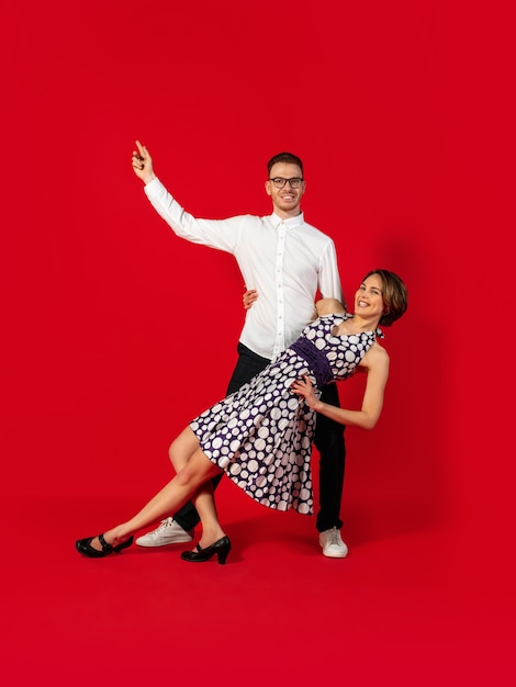 Old-school fashioned young couple dancing isolated on red background