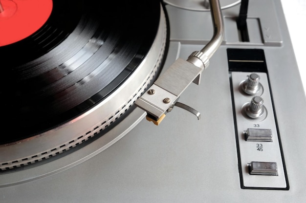 Old school turntable in silver case with vinyl record with red label isolated top view